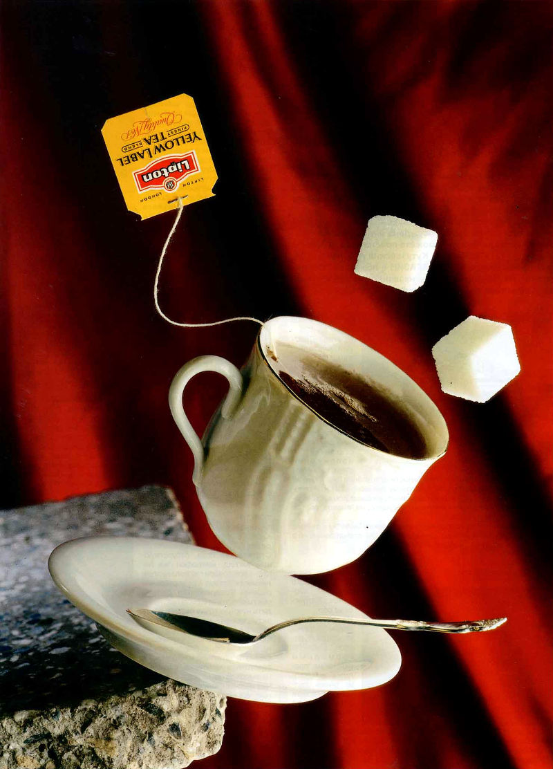 Фарфоровые чашка с чаем и блюдце, ложечка, два кусочка сахара в полете на красном фоне. Натюрморт (фото: Дмитрий Галантерник). Камера Sinar, объектив 210 мм, диафрагма f/32, выдержка 1/250 с, пленка Kodak Ektachrome 100 EPN.